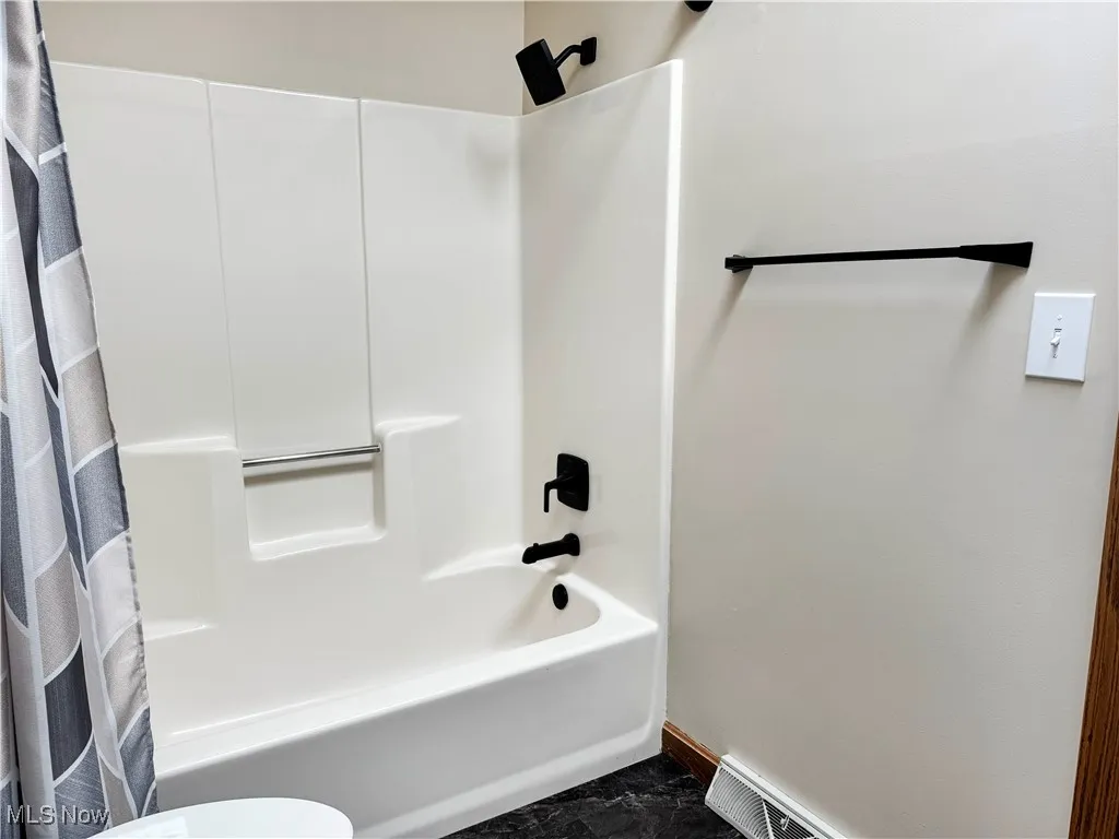 Bathroom featuring shower / bath combination with curtain and baseboards