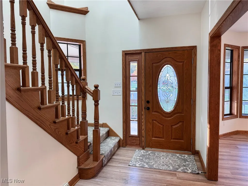 Foyer with healthy amount of natural light, light wood finished floors, and stairs