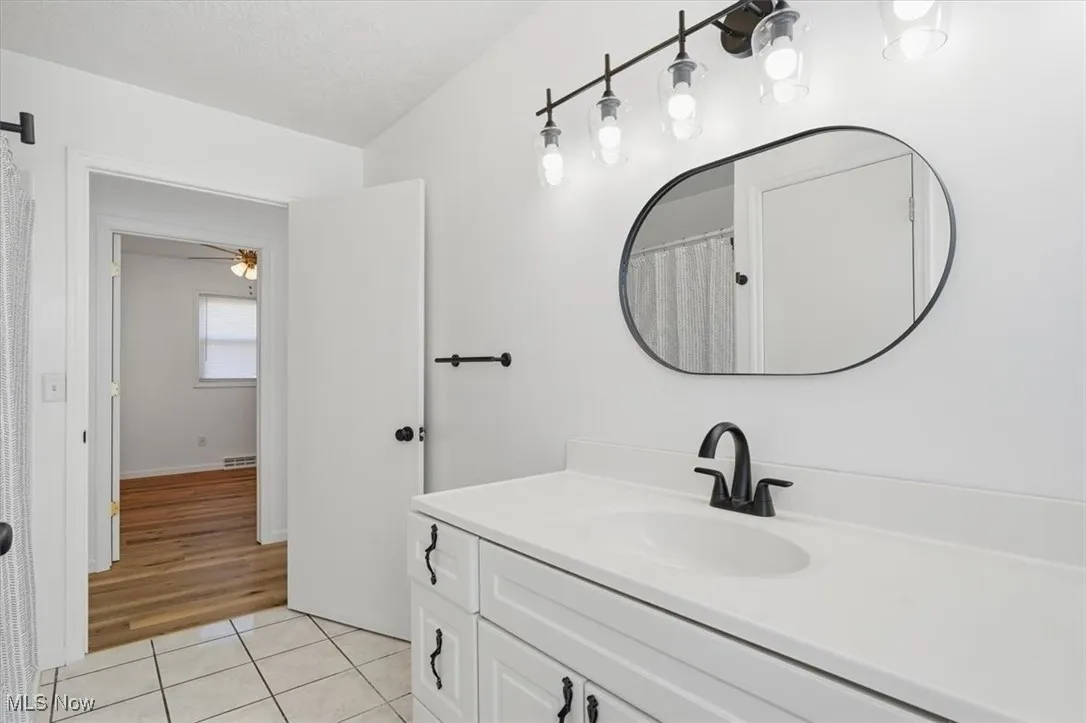 Full bath with light tile patterned flooring, vanity, and curtained shower