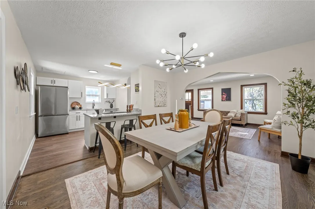 Dining space with arched walkways, a chandelier, dark wood-type flooring, and a textured ceiling