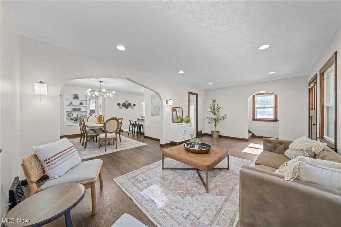 Living room with arched walkways, recessed lighting, wood finished floors, a chandelier, and a textured ceiling