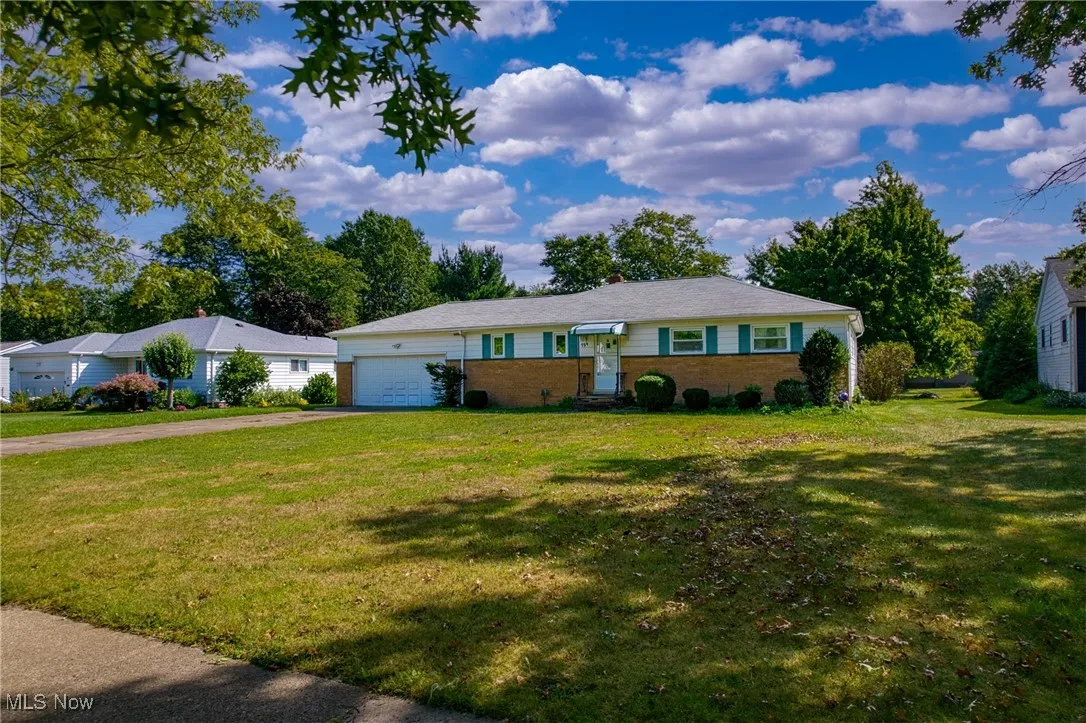 Single story home featuring driveway, a front lawn, brick siding, and a garage