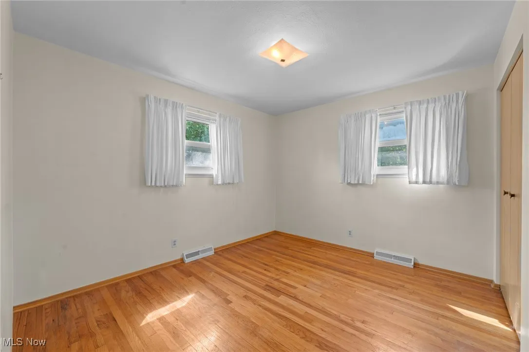 Unfurnished bedroom featuring light wood-type flooring, a closet, and multiple windows