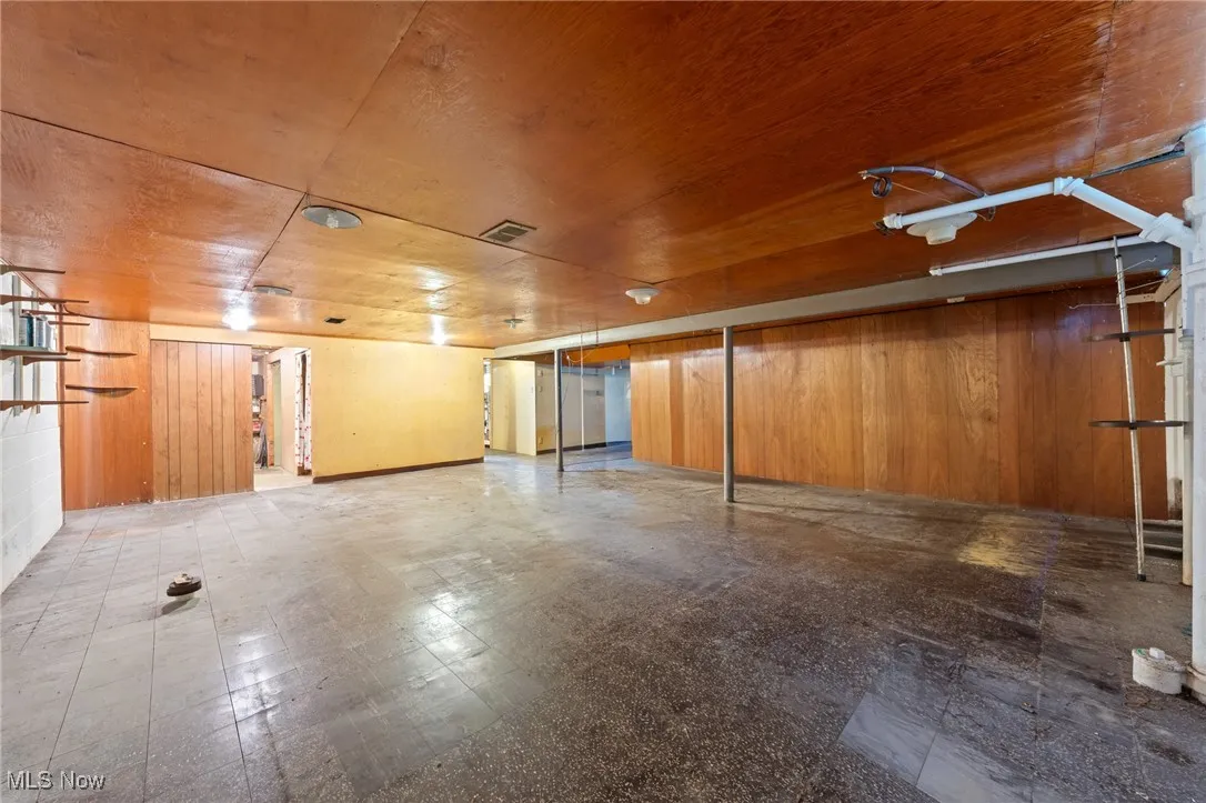 Basement featuring wood walls and tile patterned floors