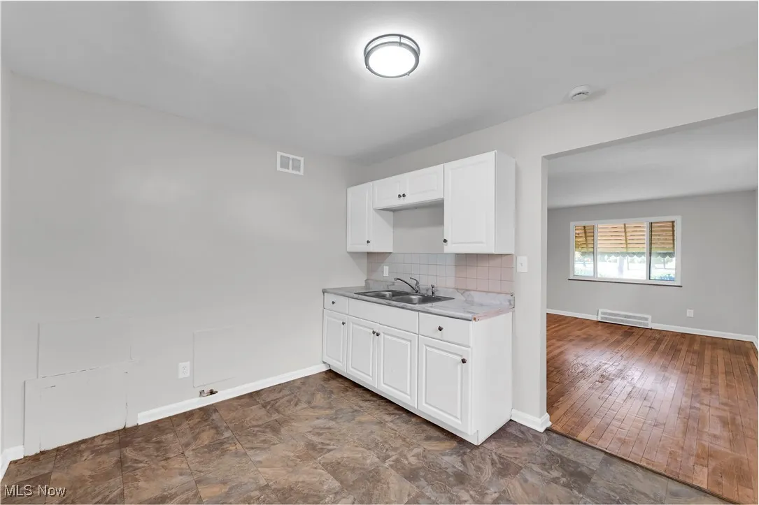 Kitchen with backsplash, white cabinetry, and light countertops
