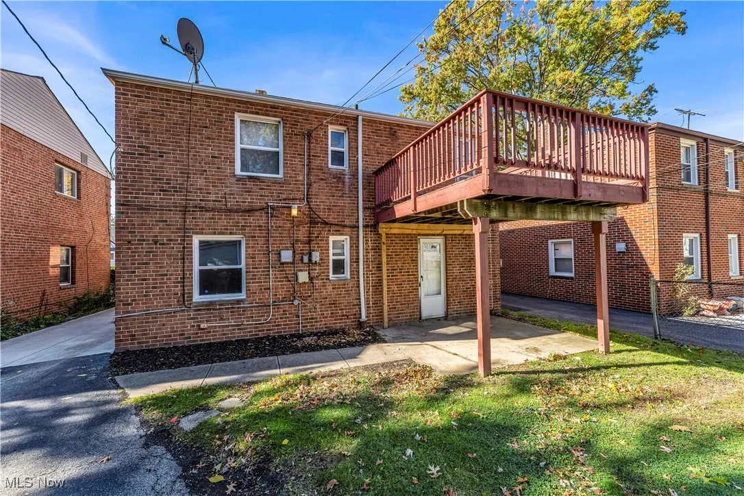 Back of house with brick siding, a patio area, a deck, and a lawn