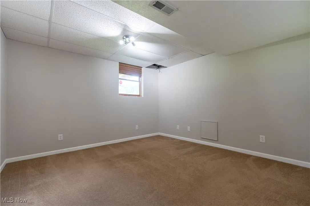 Unfurnished room featuring a paneled ceiling and light colored carpet