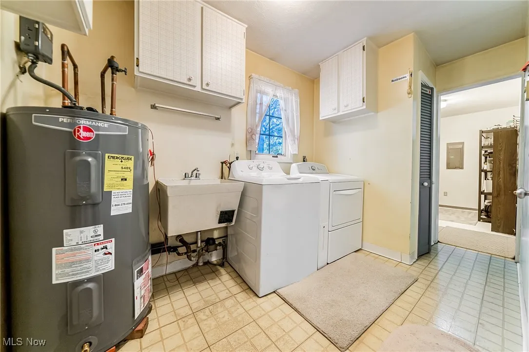 Washroom featuring water heater, cabinet space, and washer and dryer