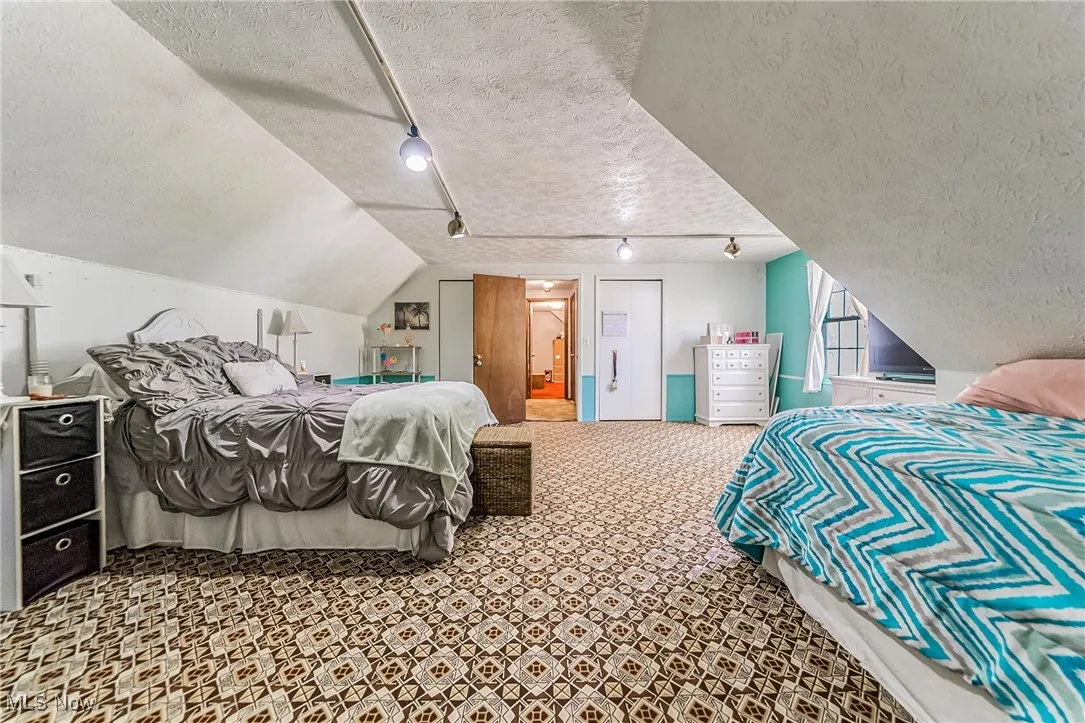Bedroom with a textured ceiling, lofted ceiling, rail lighting, and carpet floors