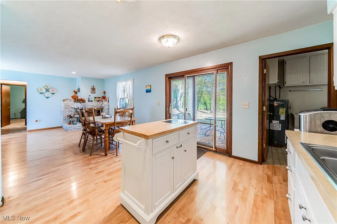 Kitchen featuring white cabinets, light wood finished floors, butcher block countertops, and water heater