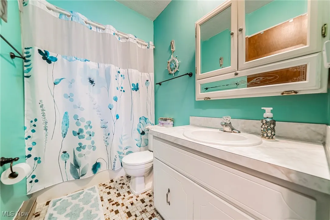 Bathroom featuring shower / bath combination with curtain, vanity, and light tile patterned floors
