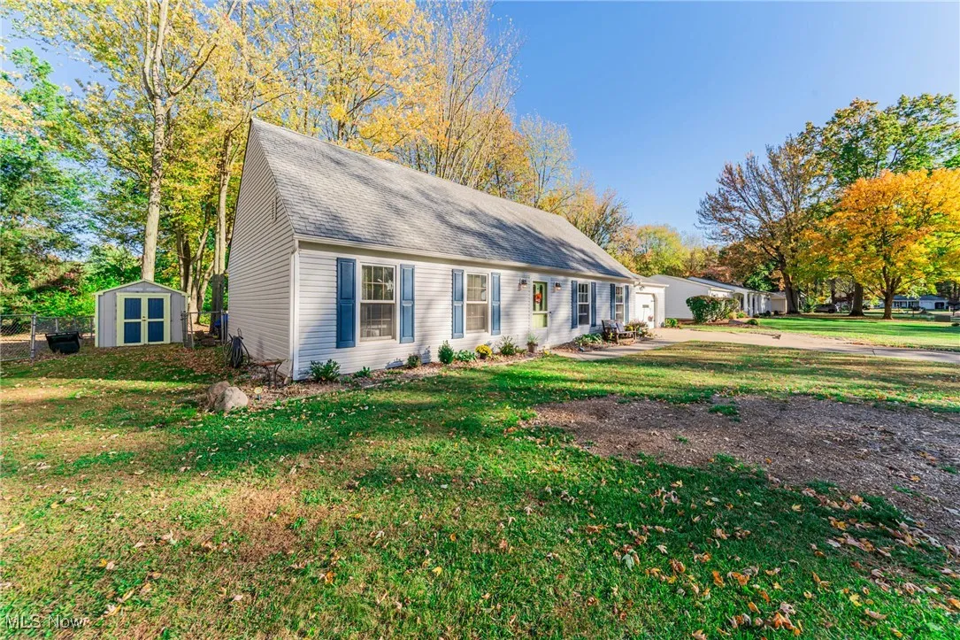 View of front of property with a storage unit, a front yard, and a shingled roof