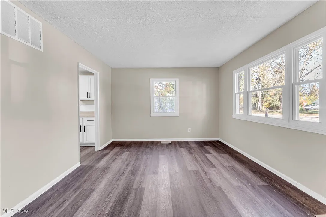 Empty room featuring dark wood-type flooring and a textured ceiling