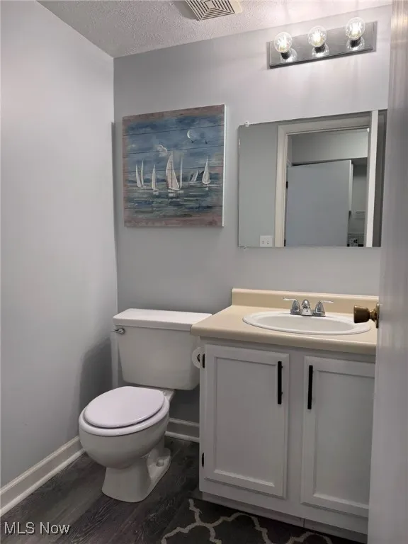 Bathroom with a textured ceiling, dark wood finished floors, and vanity
