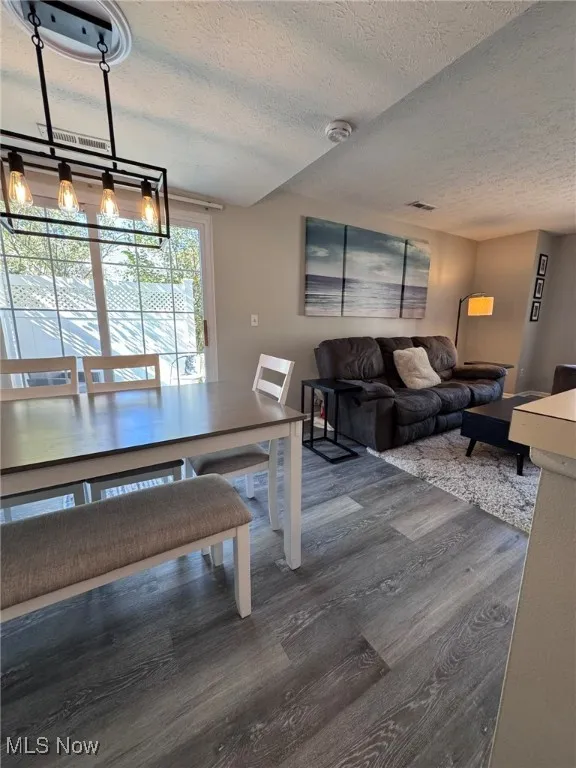 Dining room with a textured ceiling and dark wood-style flooring