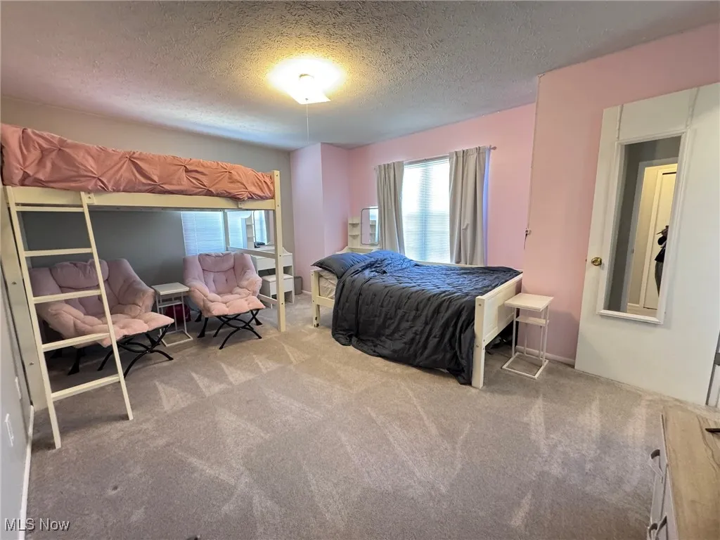 Bedroom with a textured ceiling and carpet