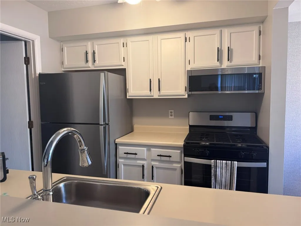 Kitchen with appliances with stainless steel finishes, white cabinets, and light countertops