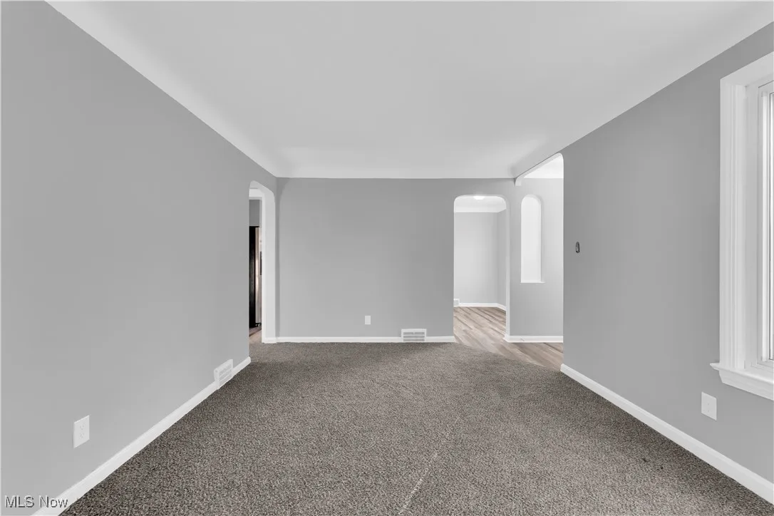 Spare room with arched walkways and light colored carpet