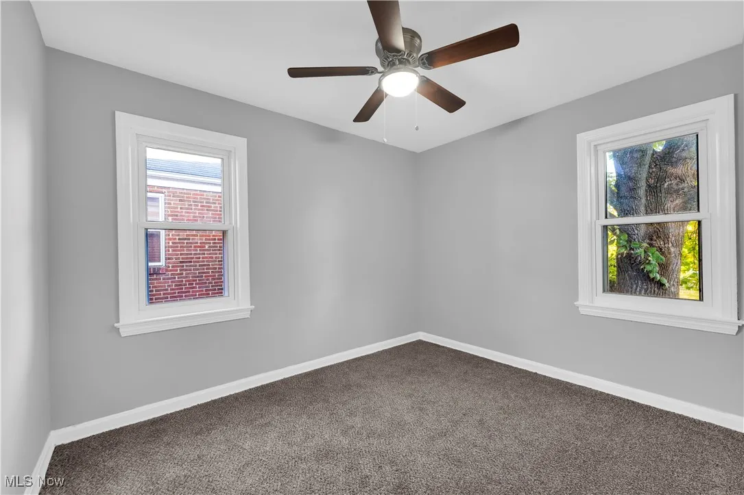 Carpeted empty room featuring plenty of natural light and ceiling fan
