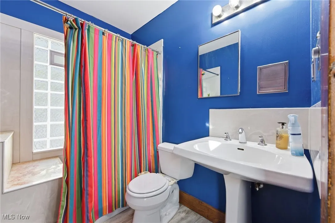 Full bathroom with a shower with curtain and wood finished floors