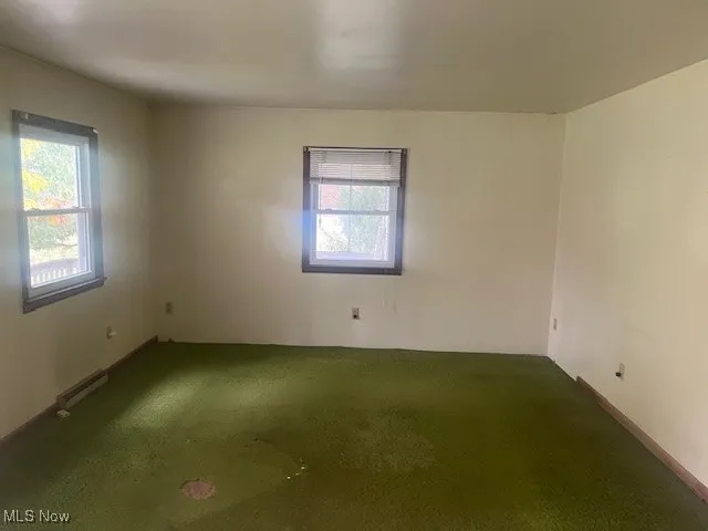 Empty room featuring carpet and baseboards