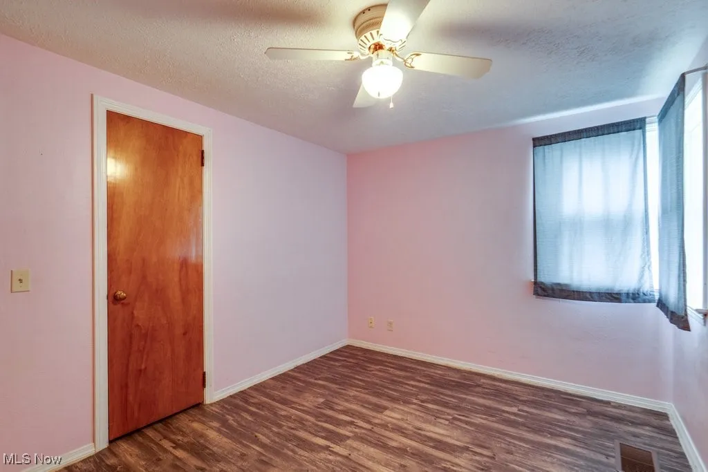 Unfurnished room with dark wood finished floors, a textured ceiling, and a ceiling fan