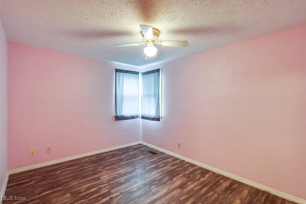 Unfurnished room featuring dark wood finished floors, a textured ceiling, and a ceiling fan