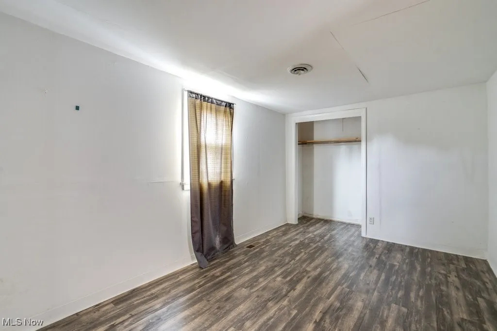 Unfurnished bedroom with dark wood finished floors and a closet