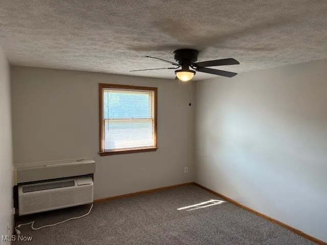 Unfurnished bedroom with a textured ceiling, carpet floors, a closet, and a ceiling fan