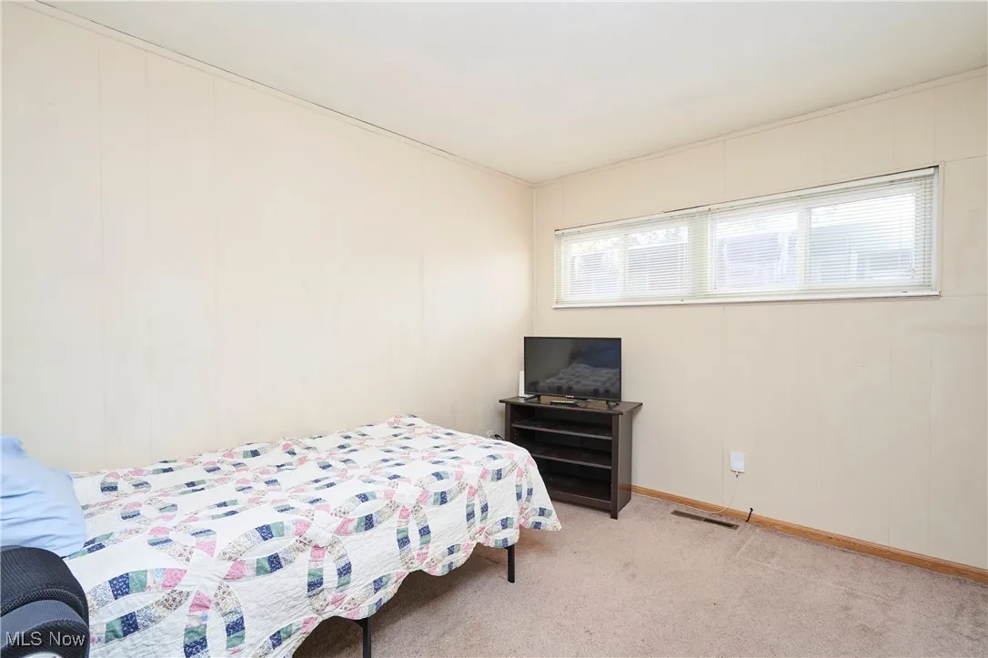 Bedroom with light colored carpet and baseboards
