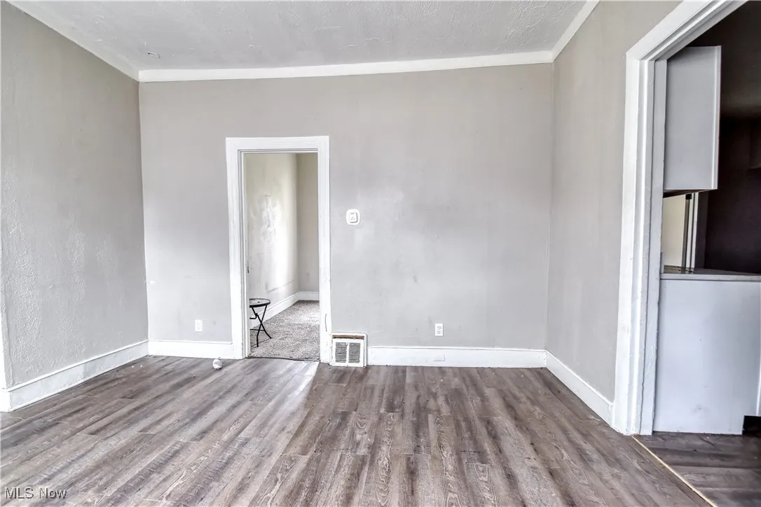 Empty room with dark wood-style floors and crown molding