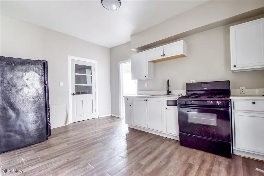 Kitchen featuring black appliances, white cabinets, and light wood-style flooring