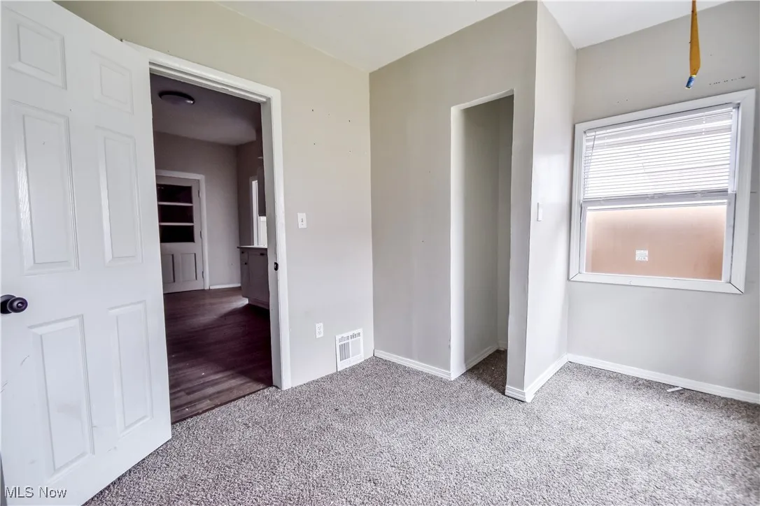 Unfurnished bedroom with light colored carpet and baseboards