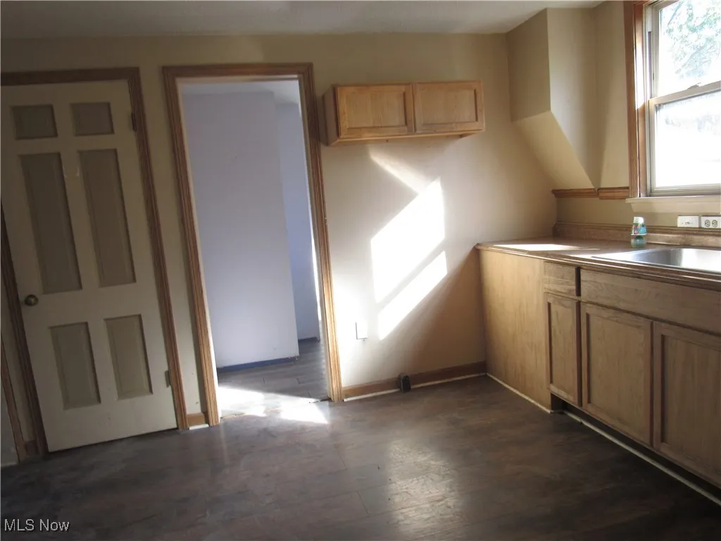 Kitchen with dark wood-type flooring, light countertops, and brown cabinetry