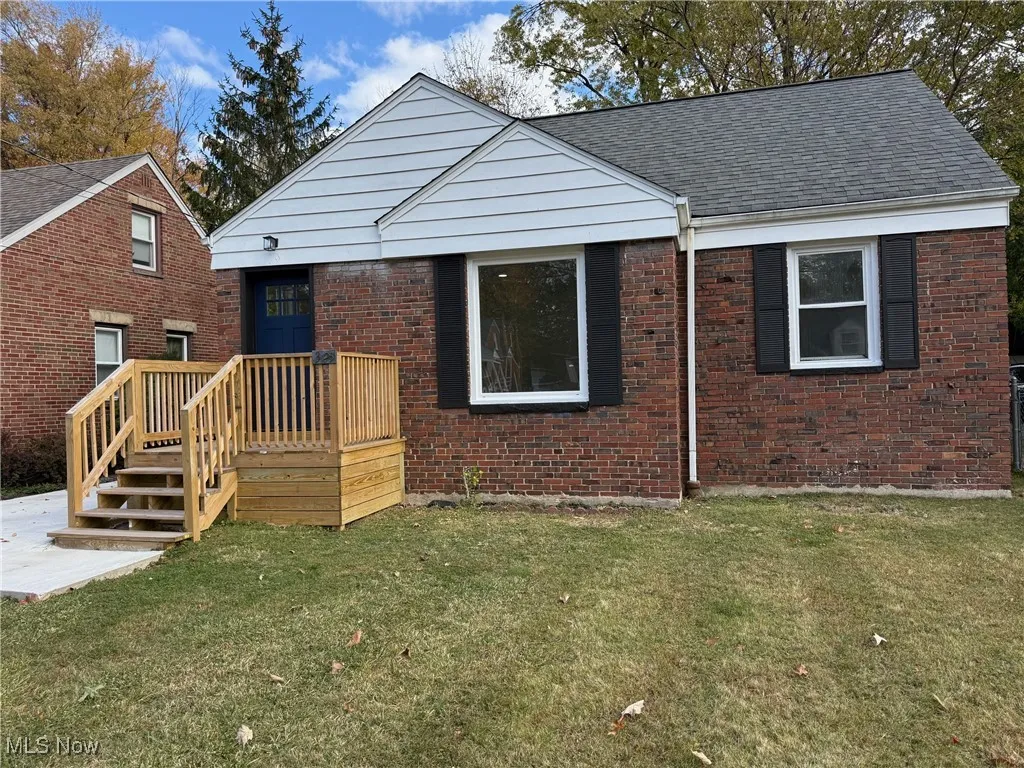 Bungalow-style house with brick siding, a front lawn, and a wooden deck