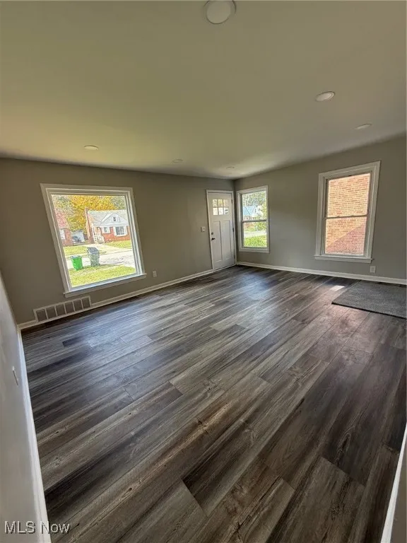 Unfurnished living room with dark wood-type flooring and recessed lighting