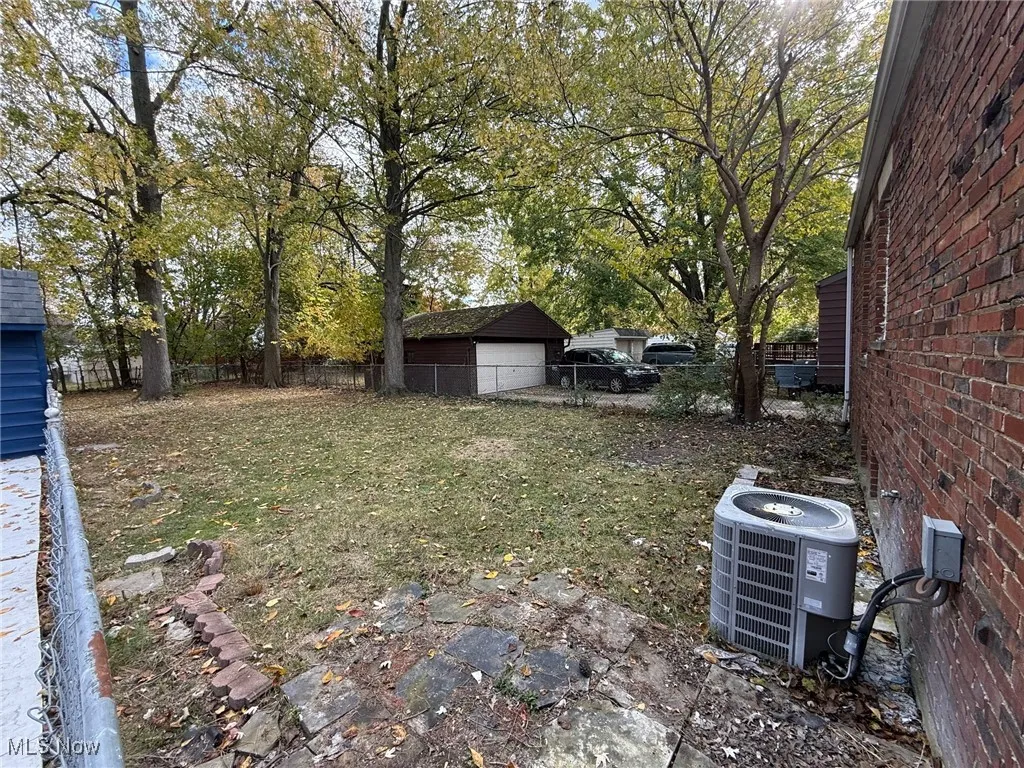 Fenced backyard featuring a detached garage and an outdoor structure