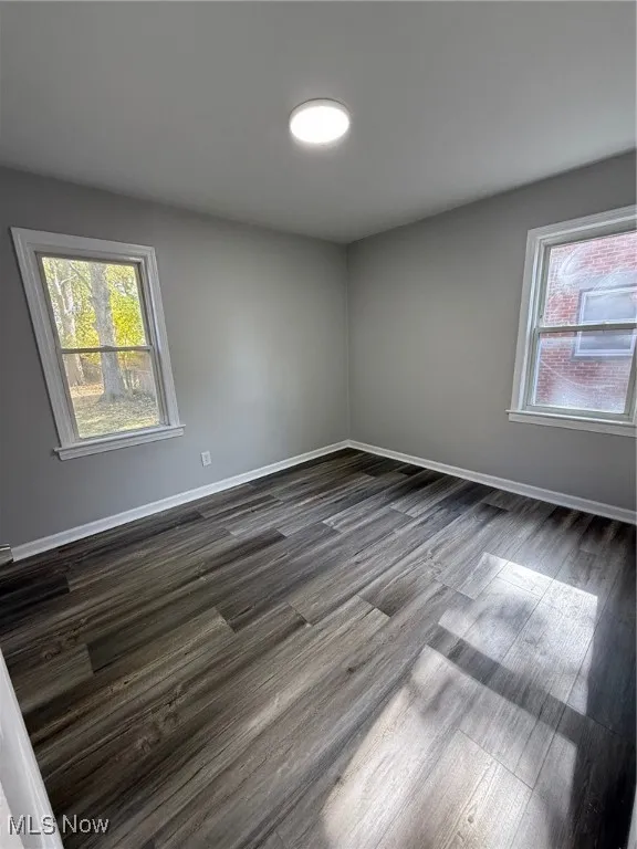 Spare room with baseboards and dark wood-style flooring