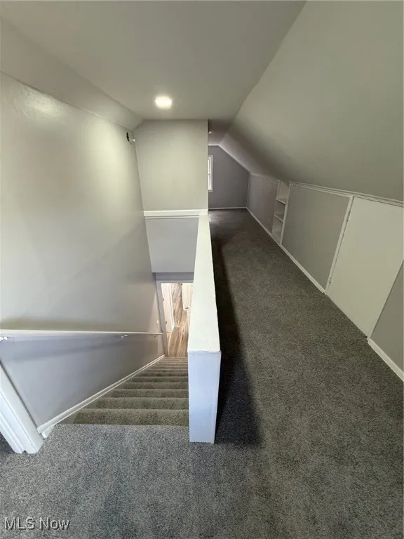 Stairway with carpet and vaulted ceiling
