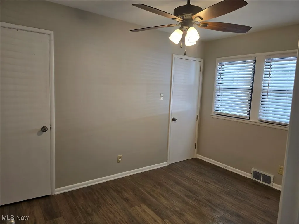 Unfurnished room with ceiling fan and dark wood-type flooring
