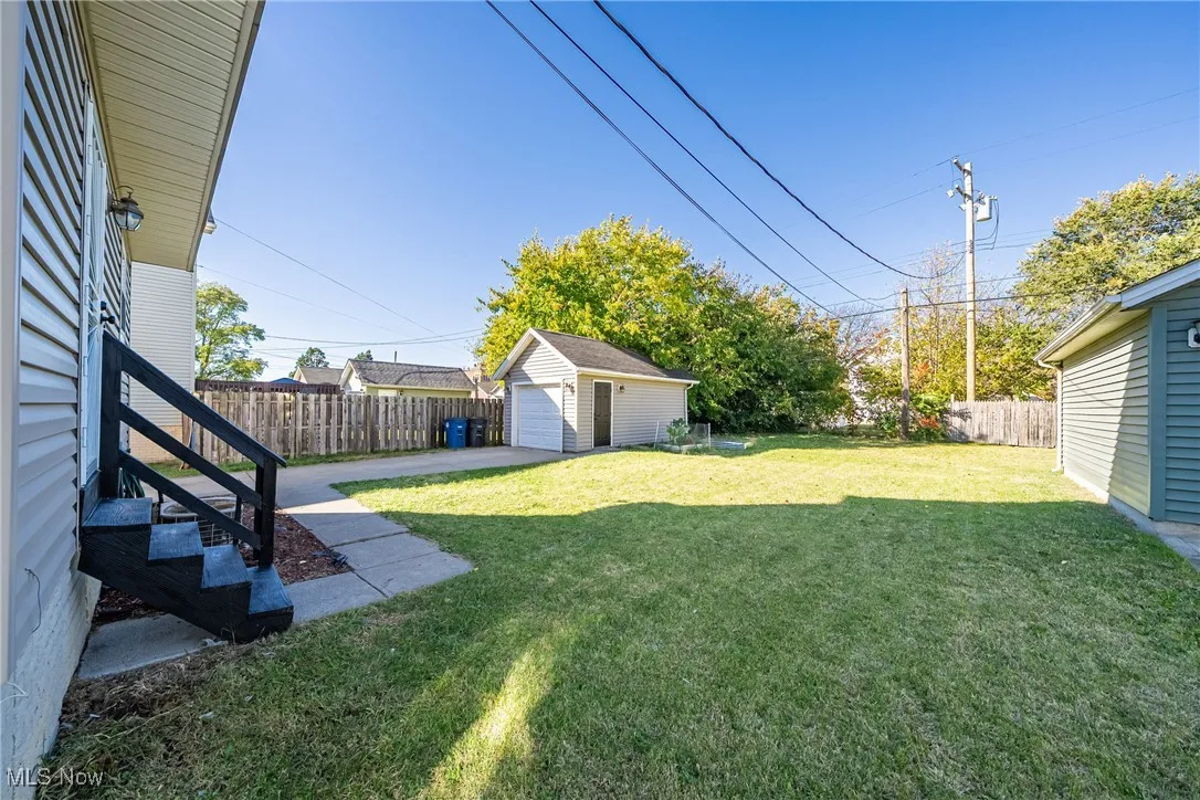 Fenced backyard with an outdoor structure, a garage, and a patio area