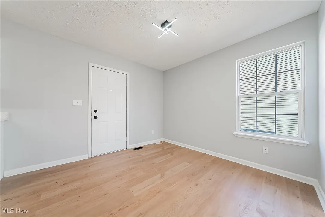 Empty room featuring light wood-type flooring and a textured ceiling