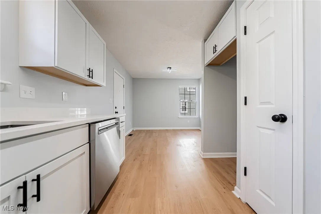 Kitchen featuring white cabinetry, dishwasher, and light wood-type flooring