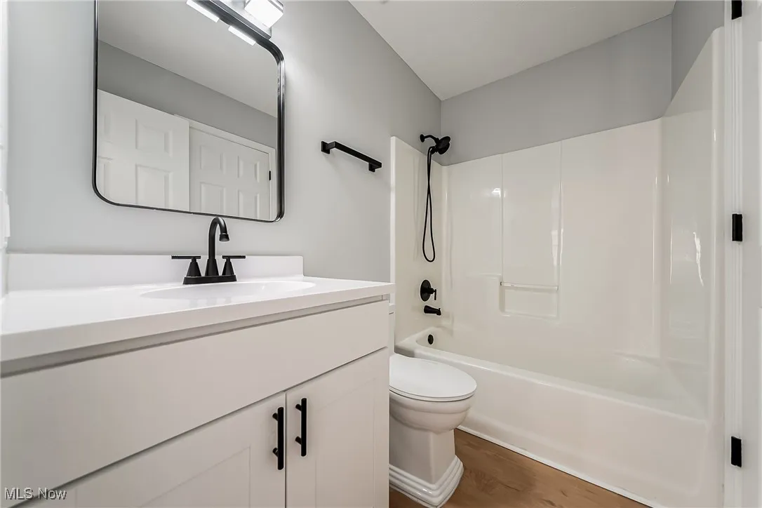 Bathroom featuring bathtub / shower combination, vanity, and dark wood finished floors
