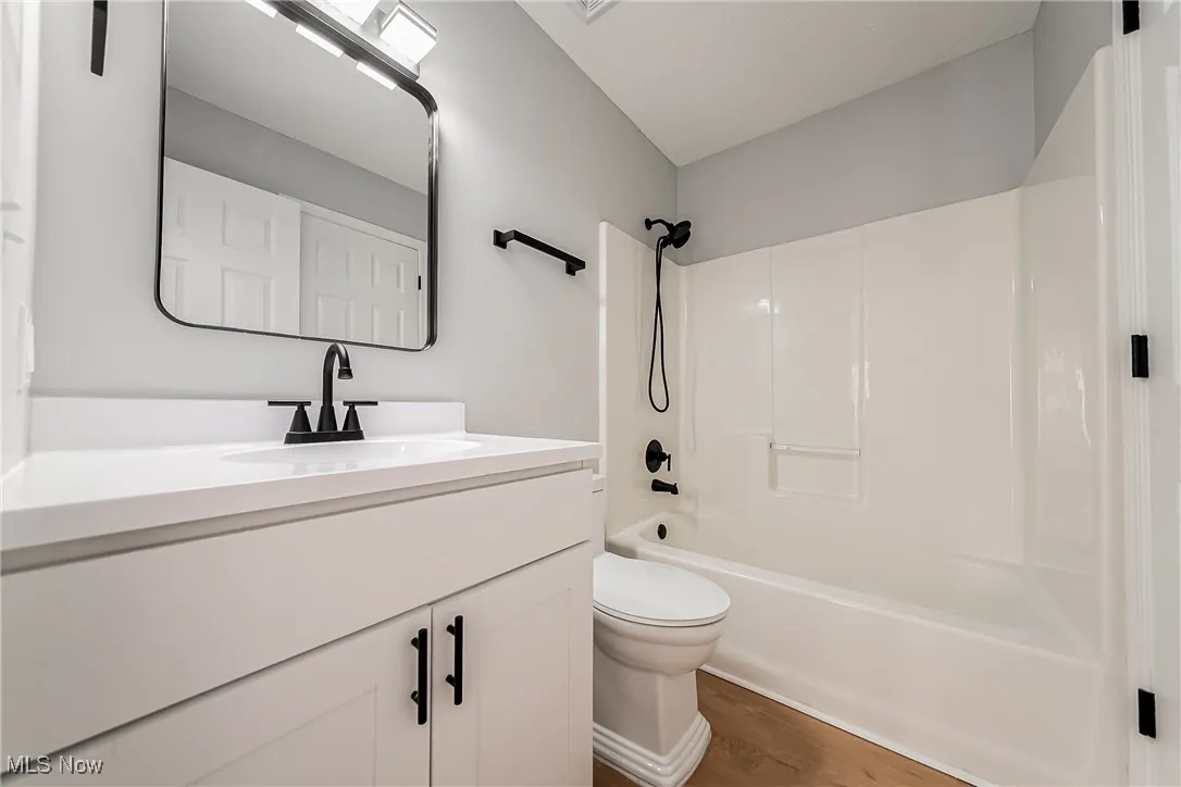 Bathroom featuring shower / bath combination, vanity, and dark wood finished floors