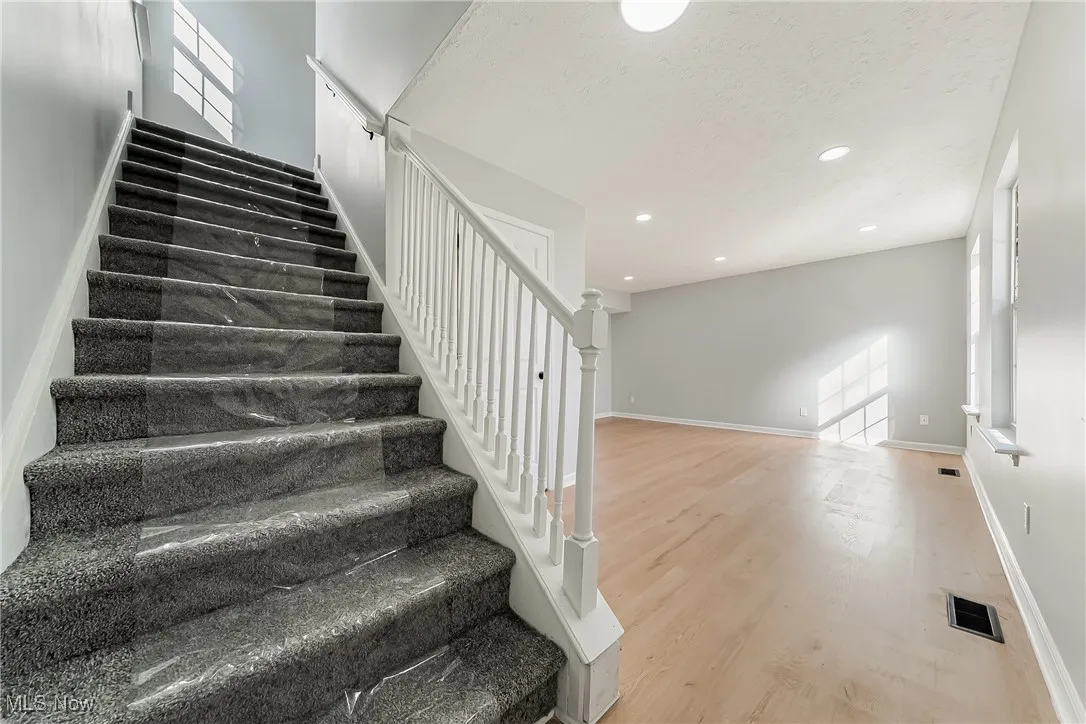 Stairs featuring wood finished floors, recessed lighting, and a textured ceiling
