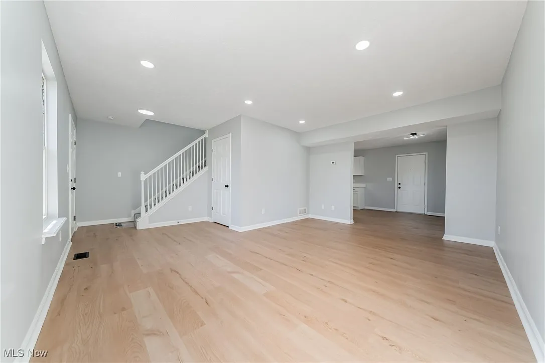 Unfurnished living room featuring light wood-type flooring, stairs, and recessed lighting