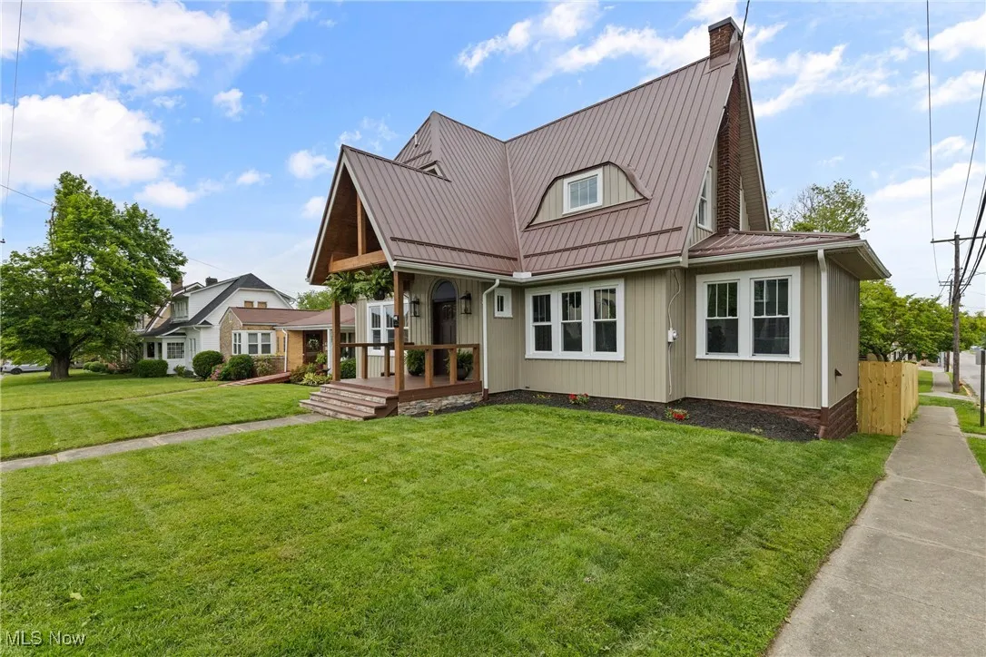 View of front of property featuring a front lawn, a chimney, a metal roof, and a deck