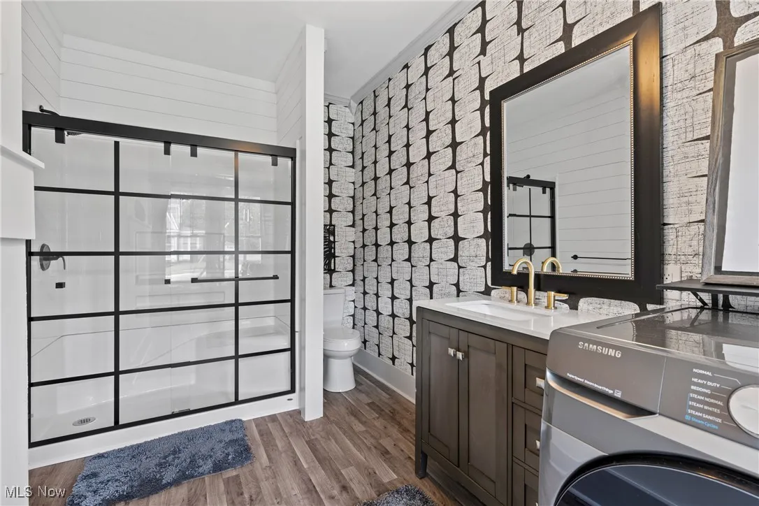 Full bathroom with washer / clothes dryer, vanity, a shower stall, and light wood-style flooring