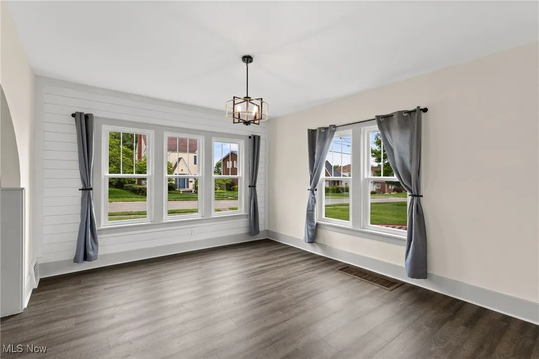 Unfurnished dining area featuring dark wood-type flooring and a chandelier